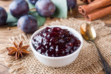 Plum jam in a bowl. Fresh plum fruit on a wooden table.