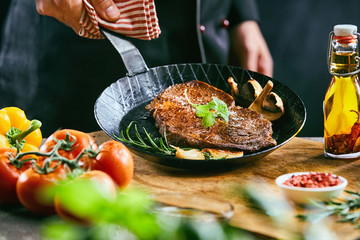 Male cook lifting up pan filled with meat