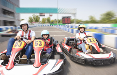 happy family driving go kart on the track - obrazy, fototapety, plakaty