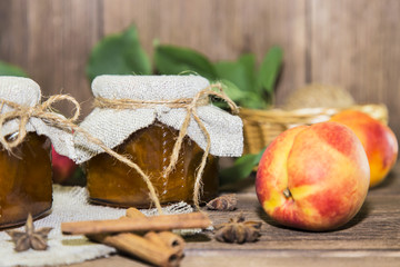 Food. Homemade canned fruit in cans. Fruit peach jam and fresh ripe peaches on the background of a wooden table in a rural style