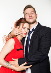 Joyful pregnant bride and groom standing together on a white background