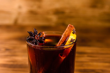 Cup of mulled wine with cinnamon on wooden table