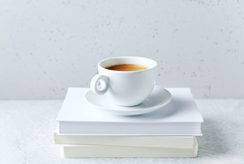 A cup of coffee on a stack of books. Copy space. Gray background