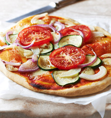 Home made vegetable pizza with zucchini, tomatoes, red onion and mozzarella.  Close-up