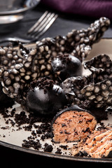 Appetizer with salmon pate, ink cuttlefish, crackers served on white tray over black wooden background. Close-up