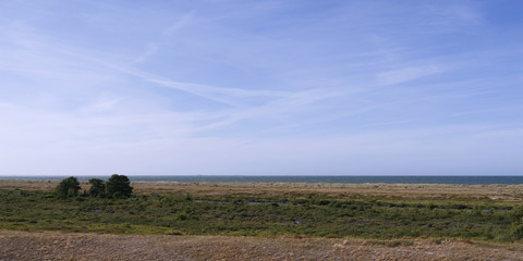 Laesoe / Denmark: View from edge of a parched heath landscape over the green coastal wetland of Holtemmen to the Kattegat Sea in the dry summer of 2018