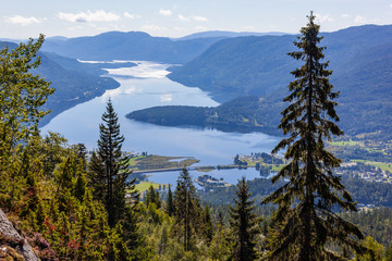 Aerial view on the vastness Norwegian landscape with small city Seljord on the shore of picturesque fjord with steep slopes covered with coniferous forest