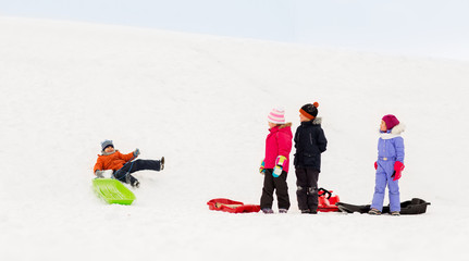 childhood, sledging and season concept - group of happy little kids with sleds in winter