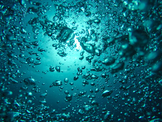 Fototapeta na wymiar Air Bubbles Going to the Surface and Towards the Sun in a Blue Sea