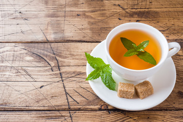 Cup of hot tea with mint and brown sugar on a wooden table Copy sapce