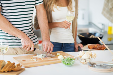 Obraz na płótnie Canvas culinary and healthy eating concept - close up of couple cooking and drinking non alcoholic wine at home kitchen