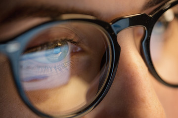 vision, business and education concept - close up of woman eyes in glasses looking at computer...