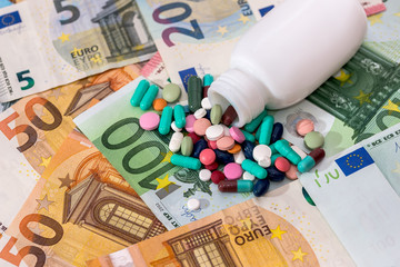Colorful pills with container on euro banknotes closeup