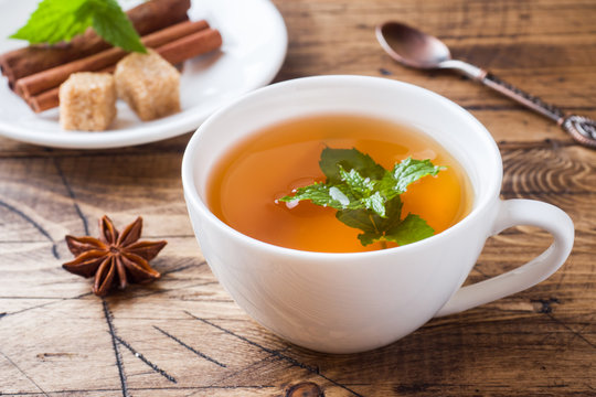 Cup of hot tea with mint and brown sugar on a wooden table