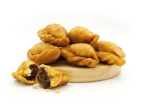 Packshot close up view of "Pan Klib" traditional mini Thai puff dessert stuffed material with fish, curry, shallot, pepper seasoned sugar and salt on wood plate isolate on white background