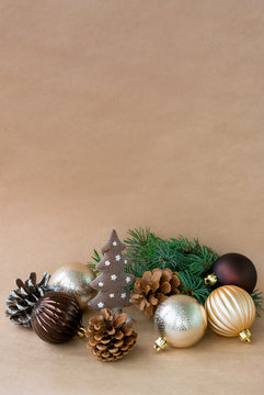Christmas toys and pine branch, cones on a dark beige background. Free space from above on a vertical photo