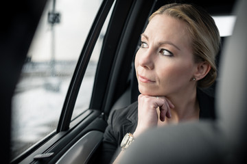 Fototapeta na wymiar Thoughtful businesswoman travelling in car looking through car window