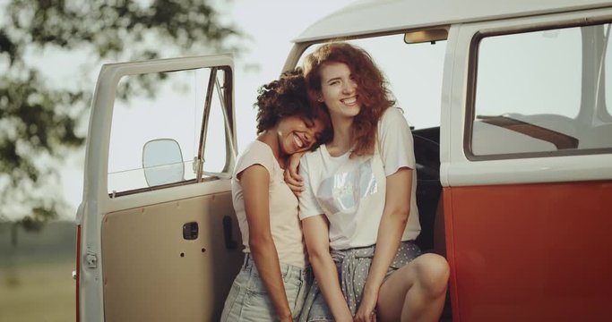Perfect smiling , of a two ladies spiriting on the retro bus and looking straight to the camera , have a curly hair. 4k