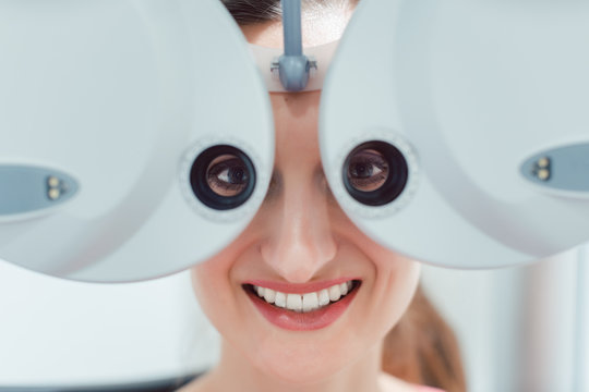 Woman having her eyesight measured with phoropter looking at the camera 