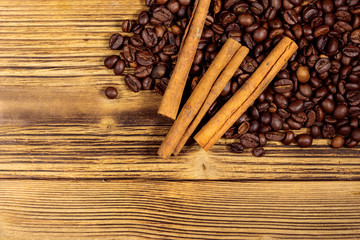 Coffee beans and cinnamon sticks on rustic wooden background. Top view