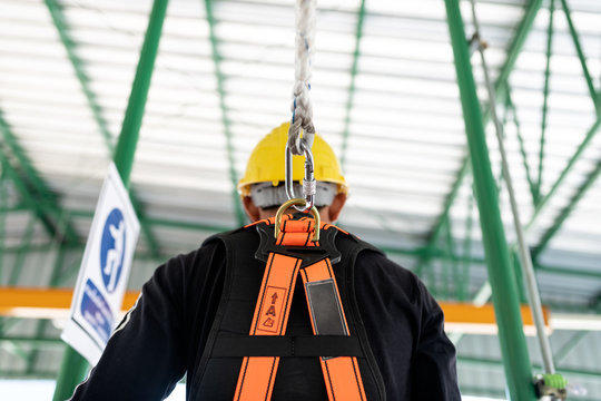 Construction worker wearing safety harness and safety line working at high place.