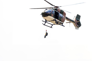 Rayong, Thailand - July 21 2018:the men lowered by a rope under a helicopter on the white...