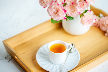 cup of tea with roses on a wooden tray