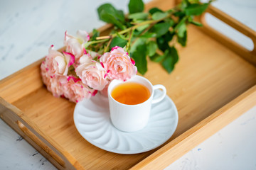 cup of tea with roses on a wooden tray