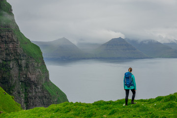 COPY SPACE: Unrecognizable woman hikes up to edge of cliff and looks at the sea