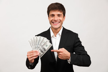 Happy businessman standing isolated holding money pointing.
