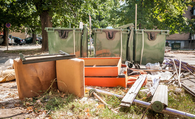 Garbage. Home furniture thrown in the garbage on the street in the city near plastic dumpster cans littering and polluting the town and environment