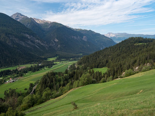 Idyllic landscape in the Alps with fresh green meadows and blooming flowers and snowcapped mountain tops in the background, Switzerland, august 2018