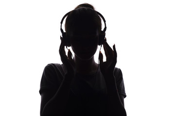 silhouette of a girl listening to music in headphones, young woman relaxing on a white isolated background