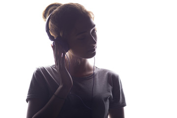 romantic girl listening to music in headphones, young woman relaxing on a white isolated background