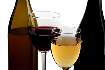 A glass of white wine and a glass of red wine next to bottles of