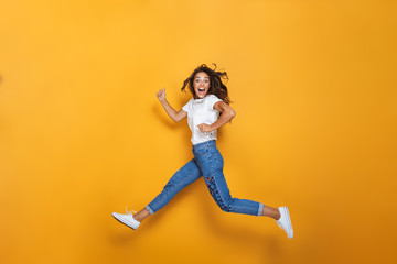 Full length portrait of a happy girl with long dark hair jumping