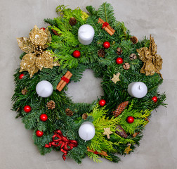 Top view, copy space. Traditional green christmas wreath with pine cones, thuja branches, candy Cane with Red Bow gift on gray concrete background. Festive decoration. Holiday concept.