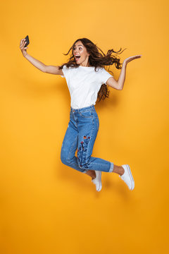 Full length portrait of a pretty girl with long dark hair jumping