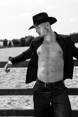 Sexy, handsome, hunky cowboy with hat open shirt and pecs looks away from camera