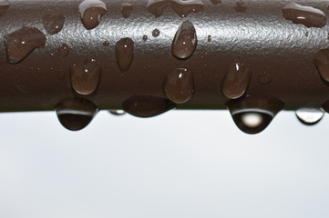 Rain drops on a brown pipe outside on a stormy day