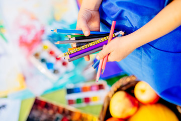 Close up of hands little girl in blue apron with brush paints drawing still life on background. Creative child painting on nature. Outdoors activity for children. Talented painter.