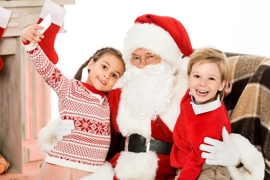 kids taking selfie with santa while sitting in armchair together