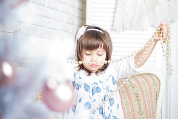 Little cute girl is decorating christmas tree/ Christmas Eve/ Merry Christmas/Happy Holidays