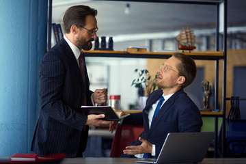 Two businessmen sitting in office and discussing new project. Business concept.