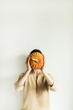 Young pretty woman holding halloween pumpkin on white background. Fall autumn concept.