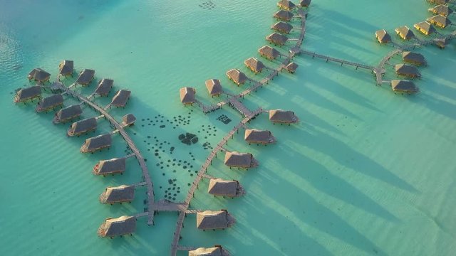Aerial footage from a drone of luxury overwater villas with palm trees, blue lagoon, white sandy beach and Otemanu mountain at Bora Bora island, Tahiti, French Polynesia (Bora Bora Aerial)
