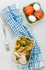 Delicious and healthy lunch. Chicken meat with boiled vegetables in container on grey background, close up.