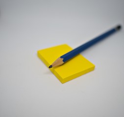 Yellow sticky note under the pencil waiting for wrting down short note.