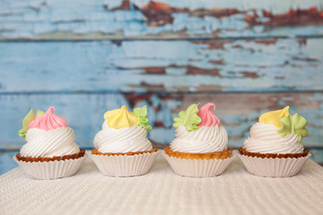 Four pink and yellow cupcakes on blue background with copy space, sweet dessert food