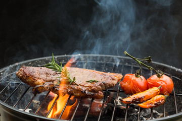 Grilling steaks on flaming grill and shot with Rosemary Pepper and Salt - Barbecue